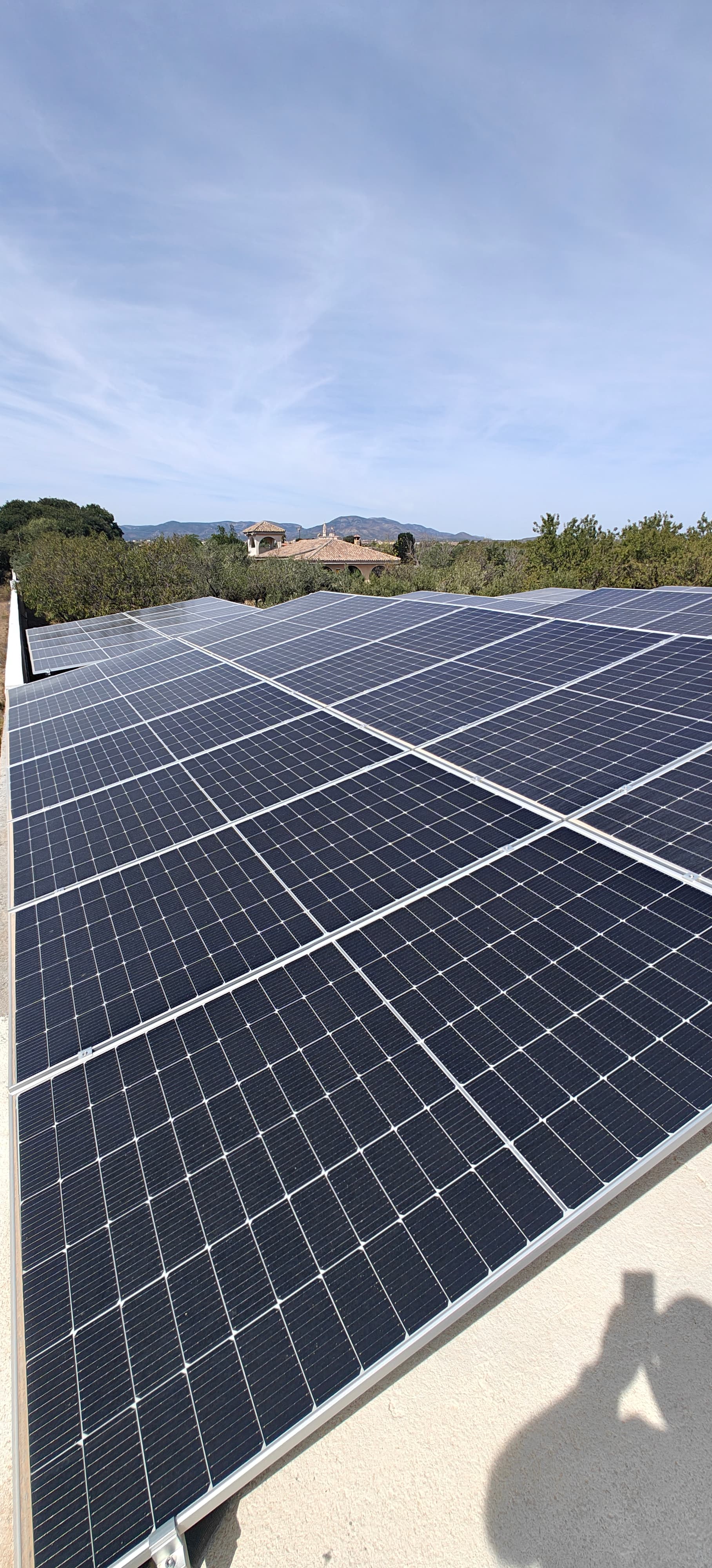 Gran conjunto de paneles solares fotovoltaicos bajo un cielo despejado con montañas al fondo.